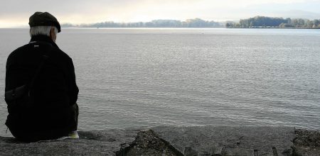 Old man siting by side of water